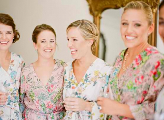 Bridesmaids smiling wearing floral robes, getting ready for the wedding