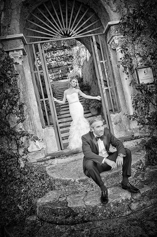Black and white wedding photo: bride and groom at gate