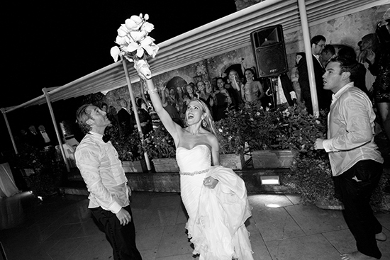 Bride tossing bouquet at wedding reception