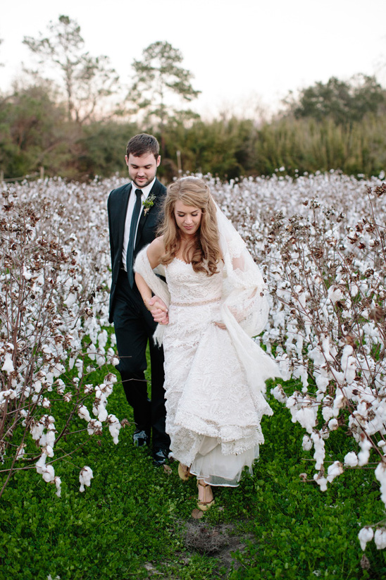 Bride and groom walking through cotton field