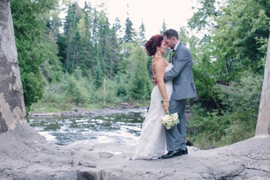 Romantic wedding couple embracing by a scenic river backdrop