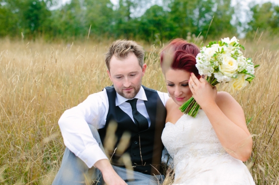 Newlyweds share a tender moment in a field of tall grass