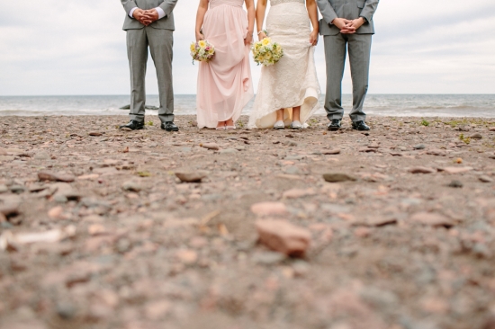 Wedding party standing on rocky beach with ocean in the background