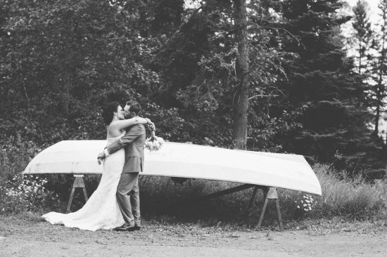Newlyweds share a kiss by a canoe on their wedding day