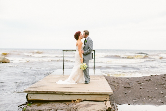 Newlyweds share a romantic kiss on a dock by the ocean