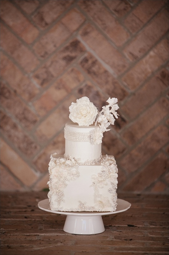 Elegant two-tiered white wedding cake with floral details and pearls