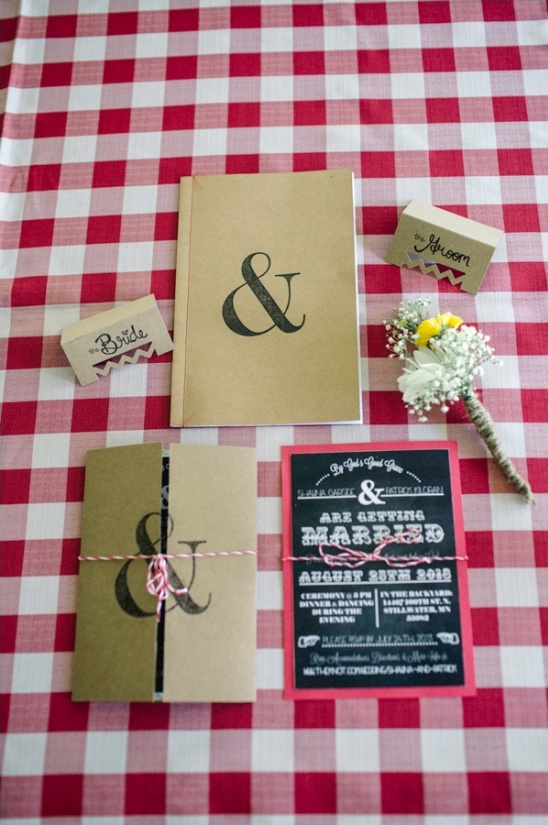Wedding decorations on red gingham tablecloth with invitation