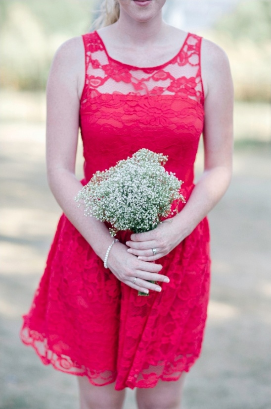 Woman in red lace dress holding a small bouquet of flowers