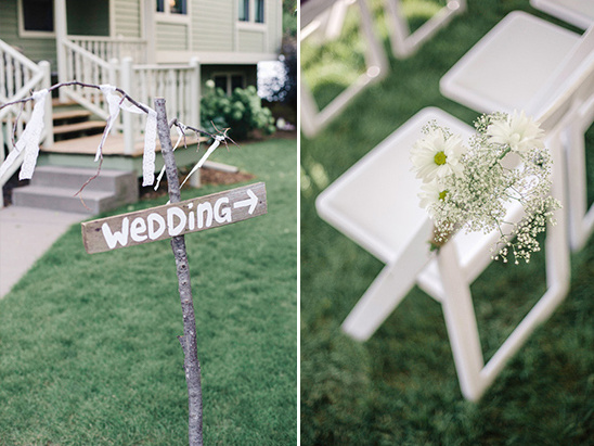 Wedding sign points the way with flowers on chairs for ceremony