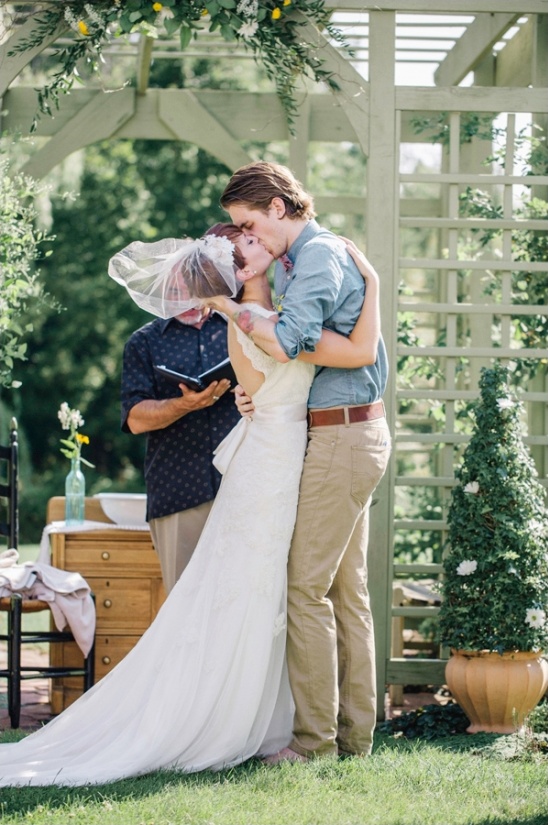 Bride and groom share a kiss during their outdoor wedding ceremony