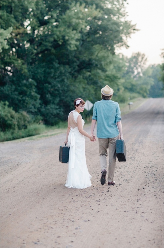 Bride and groom walk away with luggage