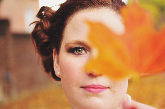 Woman with autumn leaf partially obscuring face