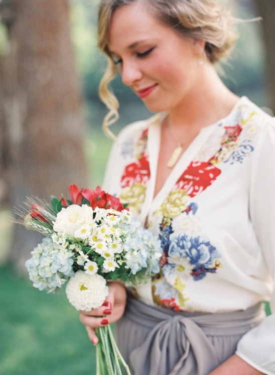 Bride holds bouquet with floral top and gray skirt