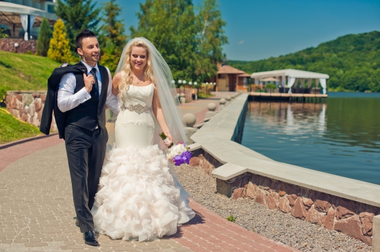 Happy couple walking after wedding ceremony by the lake