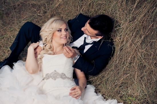 Happy couple on their wedding day smiling, laying in the grass