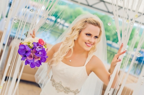 Beautiful bride smiles on her wedding day, holding a vibrant bouquet