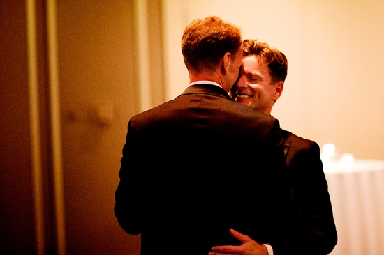 Groom smiling while being embraced by his husband