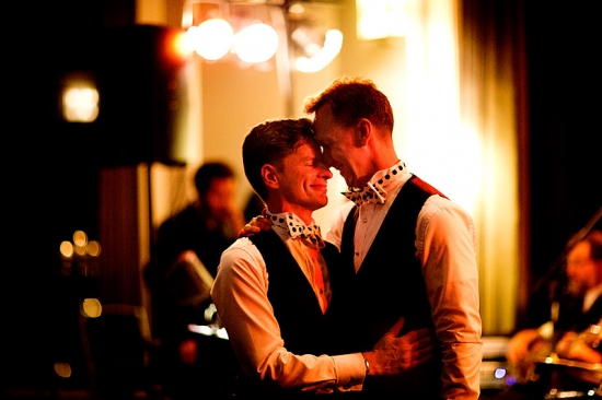 Grooms share a tender moment at their wedding reception