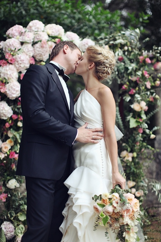 Bride and groom kissing during their beautiful outdoor wedding ceremony