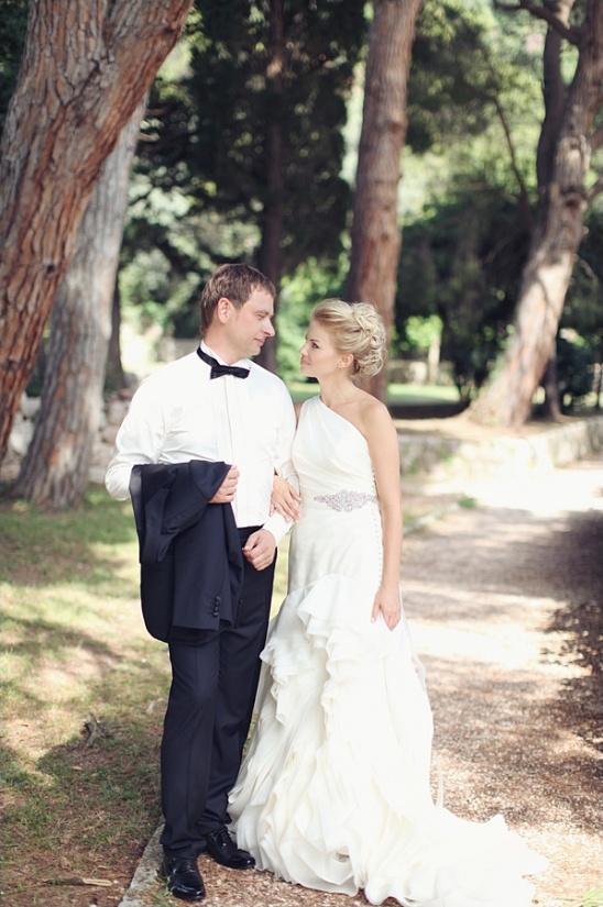 Happy couple in wedding attire walking in a sunny park, romantic