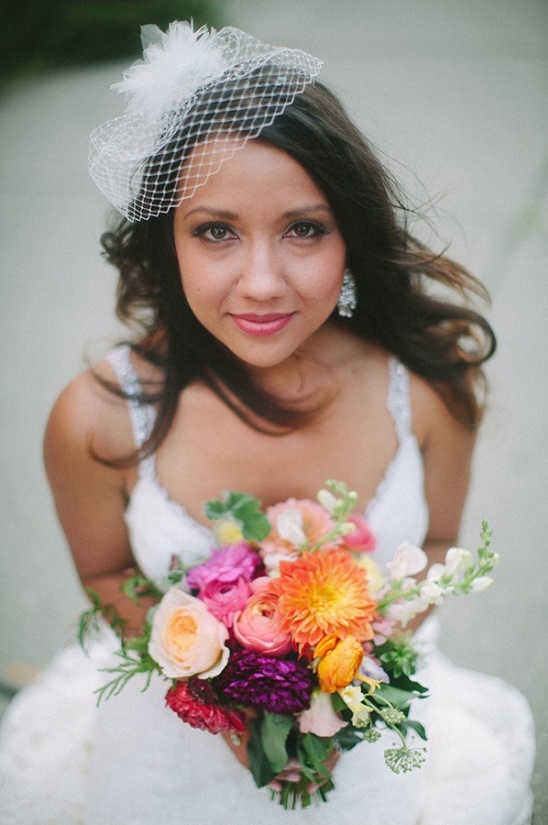 Beautiful bride smiles holding vibrant wedding bouquet
