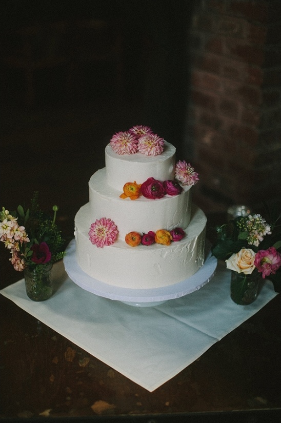 Three-tiered wedding cake decorated with fresh flowers