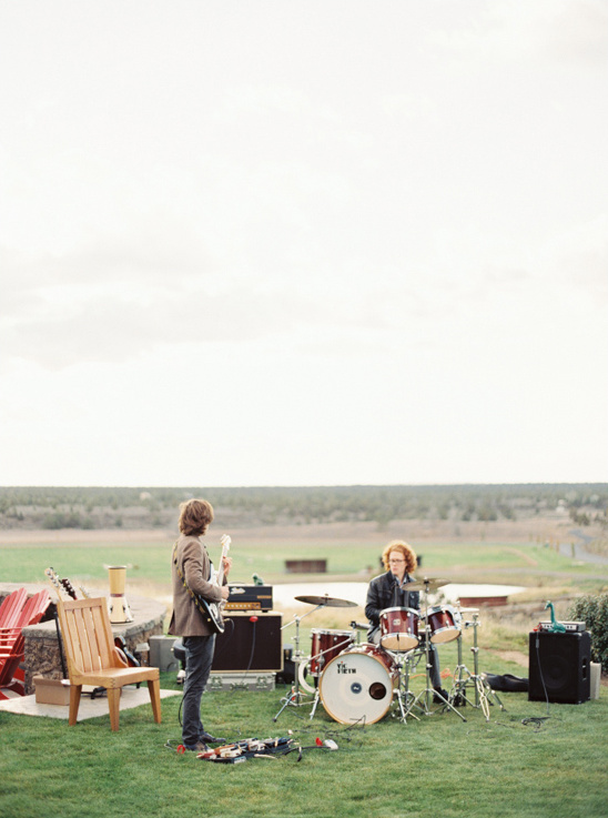 A band playing music outdoors on green grass with a cloudy sky