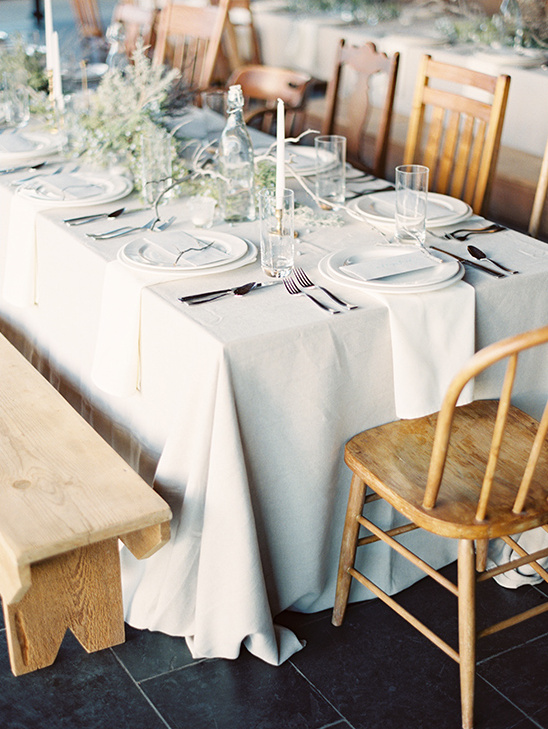Elegant rustic wedding table setting with wooden chairs and bench