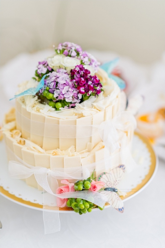 Elegant two-tiered wedding cake with flowers and butterflies