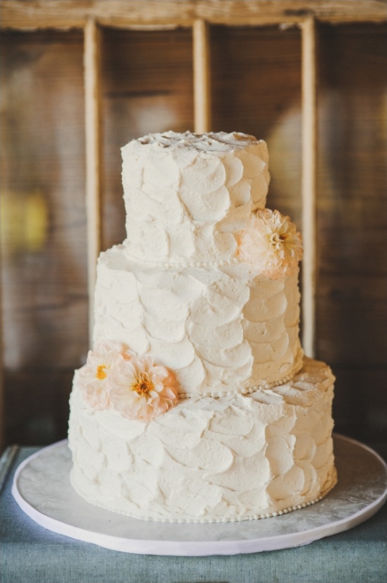 Elegant three-tiered wedding cake with floral decorations, white buttercream