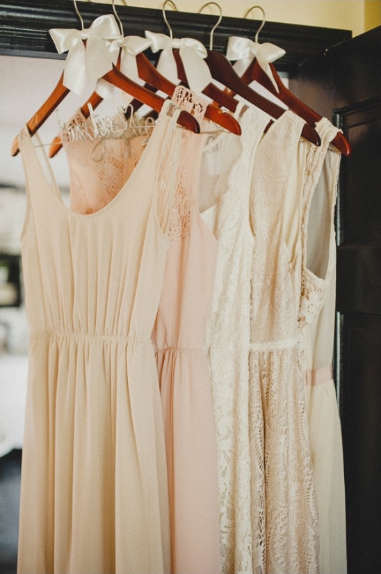 Creamy bridesmaid dresses hanging on wooden hangers