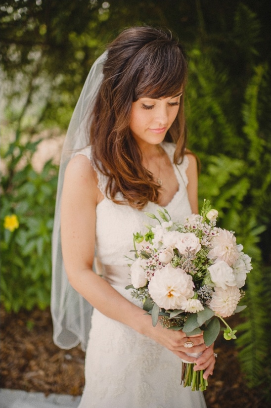 Bride with bangs holding wedding bouquet outside