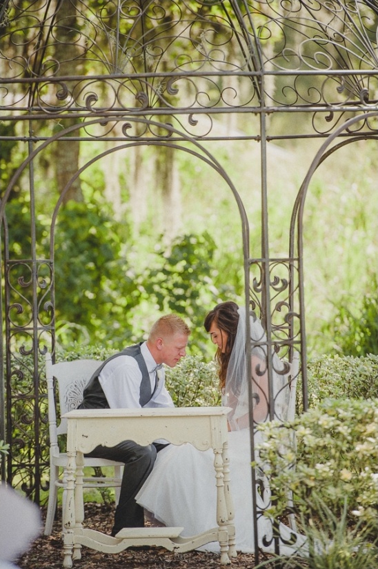 Bride and groom signing marriage license at outdoor altar