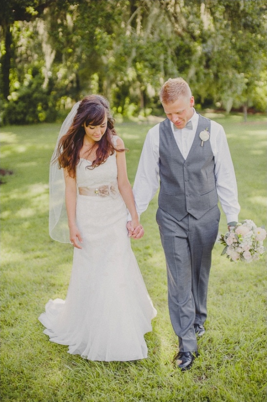 Bride and groom hold hands walking in garden