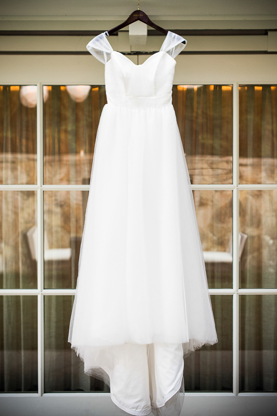 Elegant white wedding dress hanging in front of window