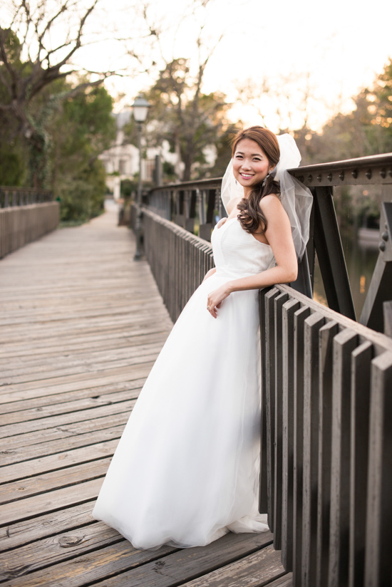 Beautiful bride in a white dress smiles on a wooden bridge