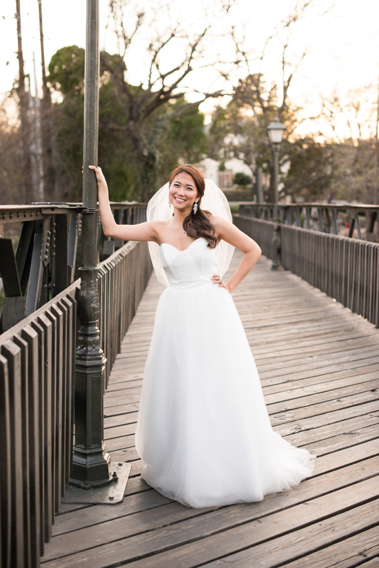 Smiling bride in elegant white dress on a wooden bridge