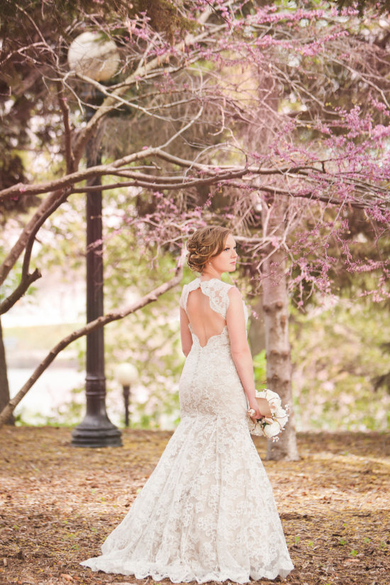 Beautiful bride in a lace wedding dress under blooming trees