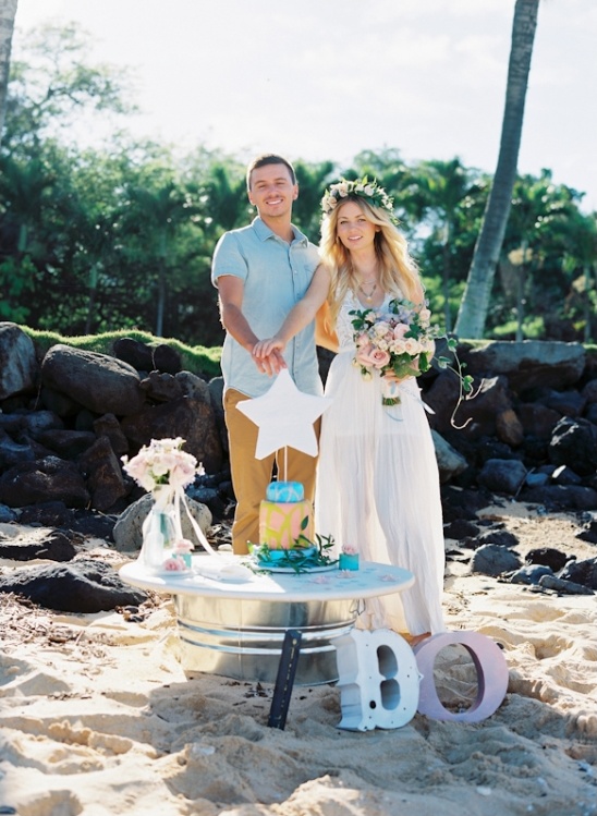 Couple cutting wedding cake on the beach, celebrating their I DOs