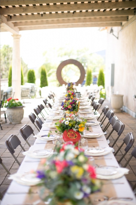 Long table set for an outdoor event with floral decorations