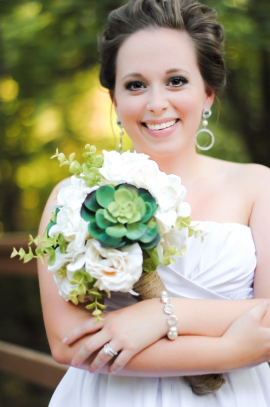 Beautiful bride smiling, holding her floral wedding bouquet