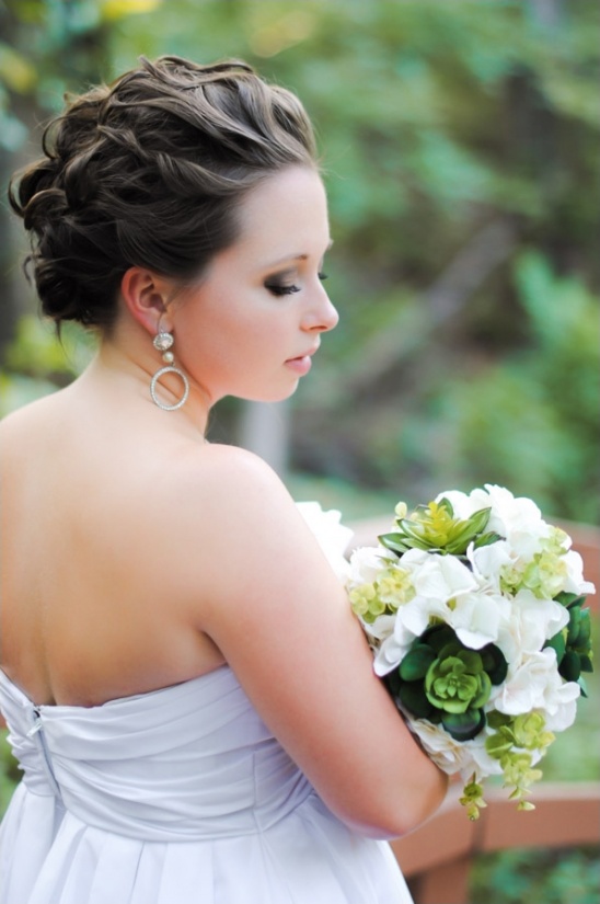 Bride holding bouquet with elegant updo hairstyle and white dress