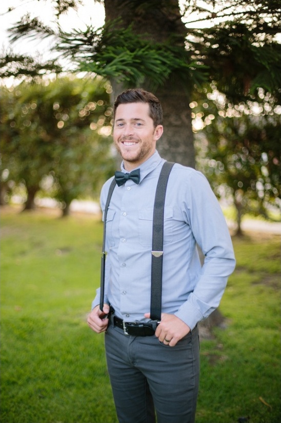 Happy man in suspenders and bow tie smiling outside