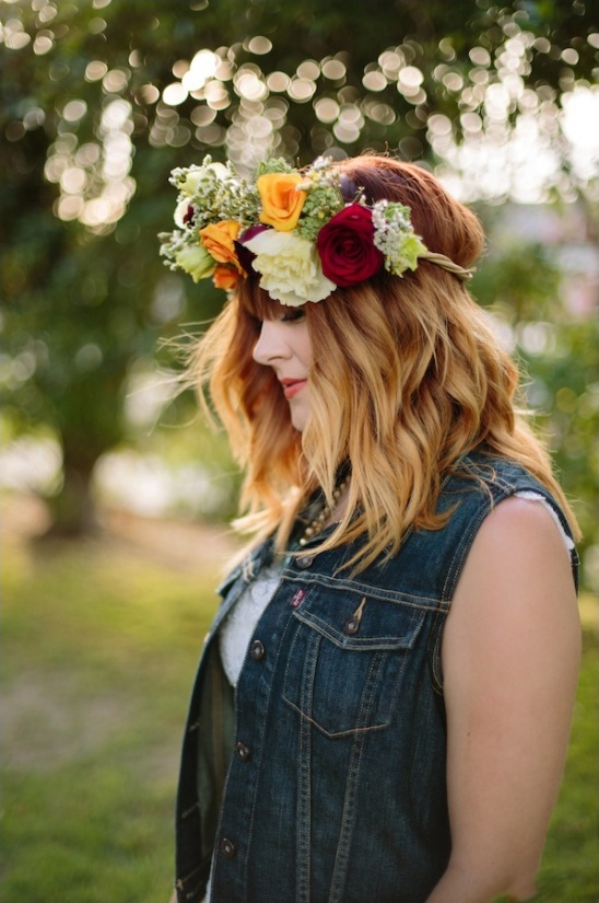 Woman wearing a floral crown and denim vest in soft sunlight