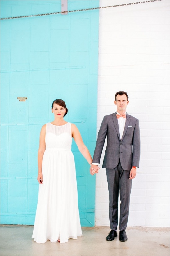 Bride and groom holding hands in front of a blue door