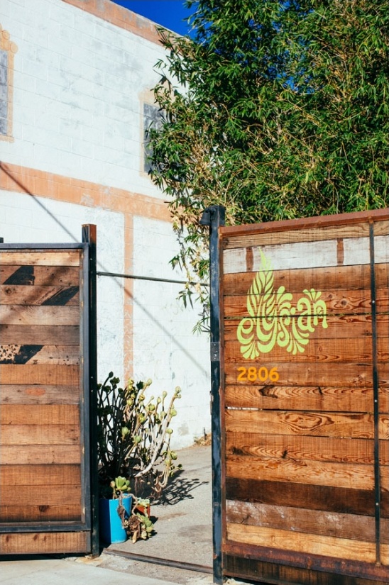 Wooden gate with address, plants, and building in sunny location