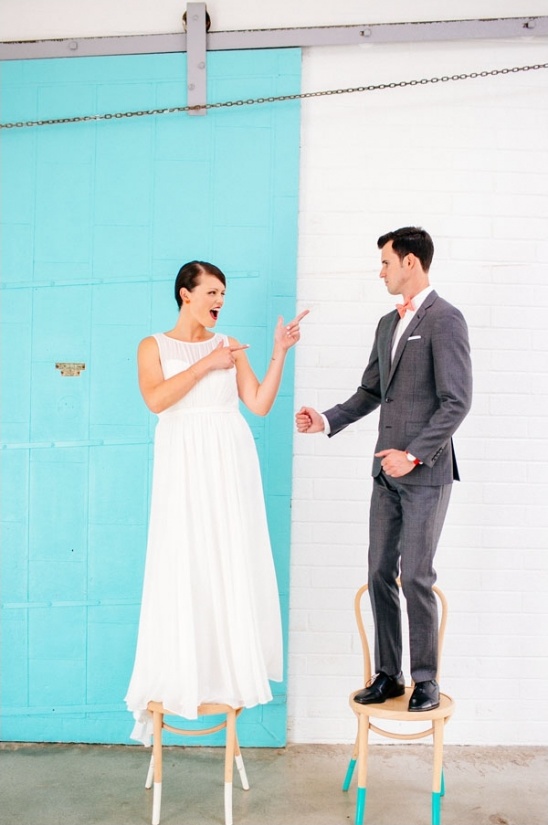 Bride and groom playfully pointing at each other on chairs