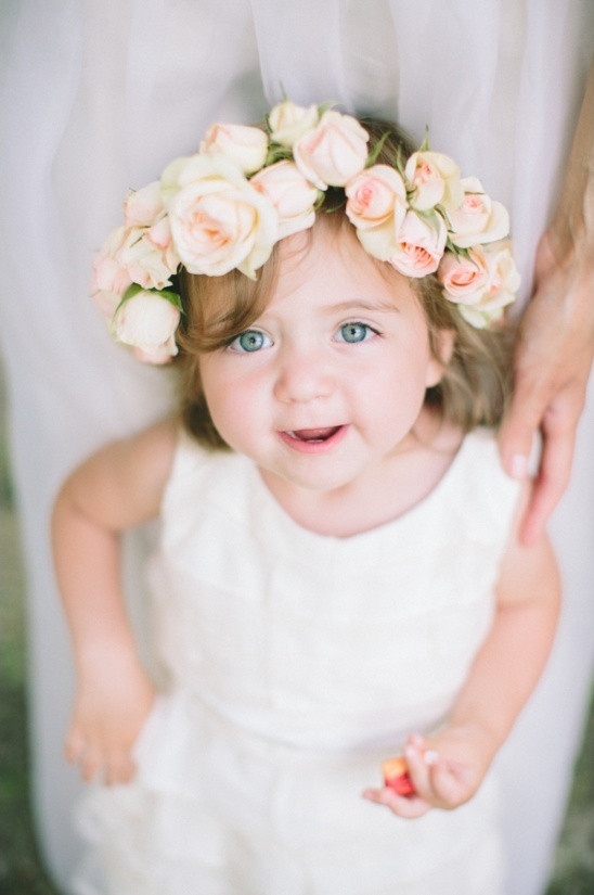 Cute flower girl with rose crown and blue eyes