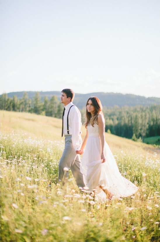 Couple walking in sunny field, wedding day
