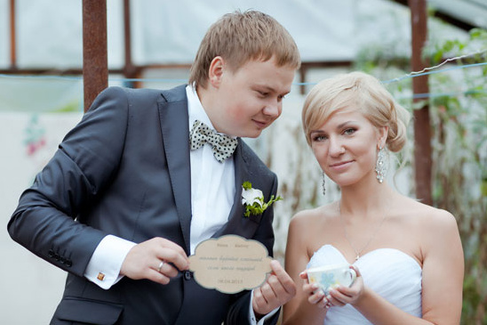 Newlyweds posing with wedding announcement card